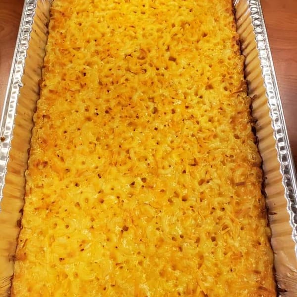 A large rectangular aluminum pan filled with golden-brown baked macaroni and cheese.