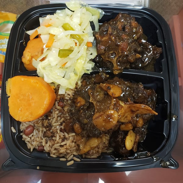 Jamaican Cafe Cuisine's oxtail stew with rice and peas, steamed cabbage, and plantains in a takeout container.