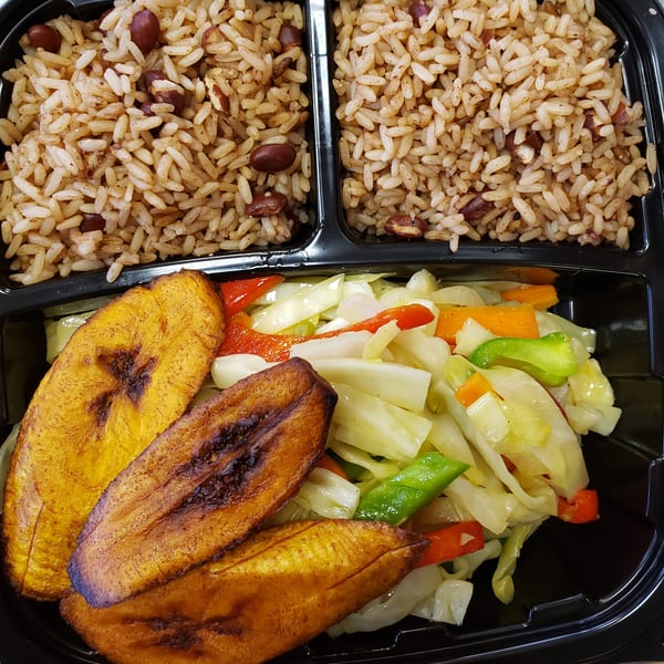 Jamaican rice and peas, fried plantains, and steamed cabbage in a black takeout container.