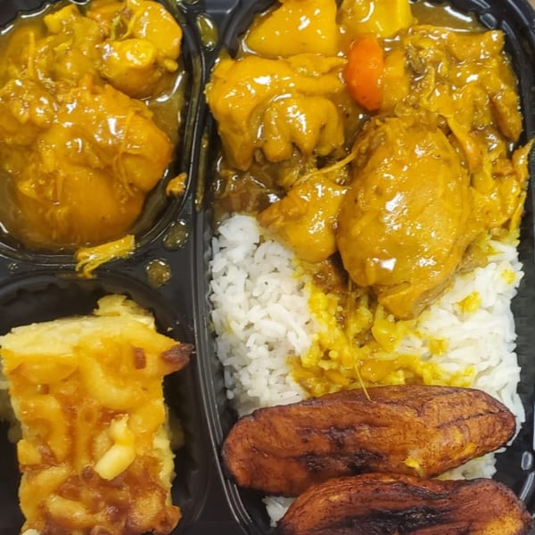 Jamaican Cafe Cuisine's curry chicken with rice, macaroni pie, and fried plantains in a takeout container.